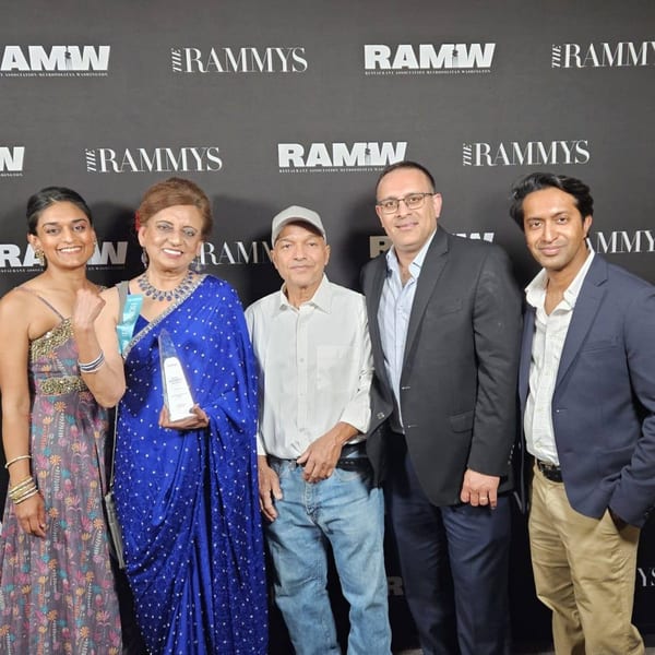 Five people, including two women holding awards, pose in front of a black RAMMYS backdrop.