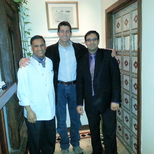 Passage to India chef and owner posing with Paul Ryan in front of a decorative door.